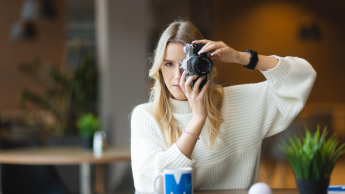 Social media i influencer marketing | Studia podyplomowe w Łodzi | Uniwersytet WSB Merito Łódź: Studentka pozuje z aparatem do zdjęcia.