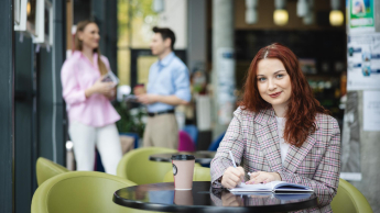 Digital marketing | Uniwersytet WSB Merito Łódź: Studentka zapisuje notatki, a obok stoi kawa.