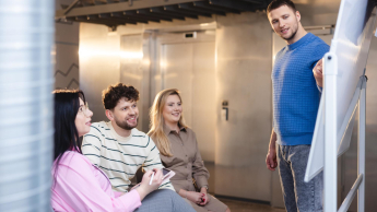 Digital marketing | Studia II stopnia ze studiami podyplomowymi  | Uniwersytet WSB Merito Łódź: Student prezentuje na tablicy, a trójka słucha.