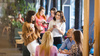 Well-being w organizacji – nowoczesne podejście do zdrowia, relacji i efektywności | Studia podyplomowe w Łodzi | Uniwersytet WSB Merito Łódź: Grupa ludzi rozmawia przy stole.