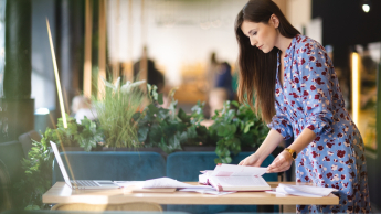 Logistyka | Studia II stopnia ze studiami podyplomowymi w Łodzi | Uniwersytet WSB Merito Łódź: Studentka stoi na stołem z notatkami.