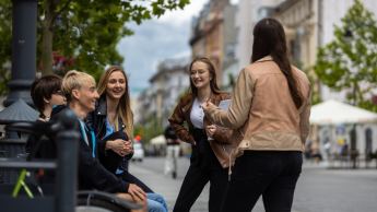 Doradztwo zawodowe i coaching kariery | Studia podyplomowe w Łodzi | Uniwersytet WSB Merito Łódź: Grupka studentów rozmawia śmiejąc się na mieście.