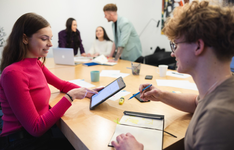 Marketing in the digital economy | Studia II stopnia w Łodzi | Uniwersytet WSB Merito Łódź: Grupa studentów siedzi przy stole i rozmawia