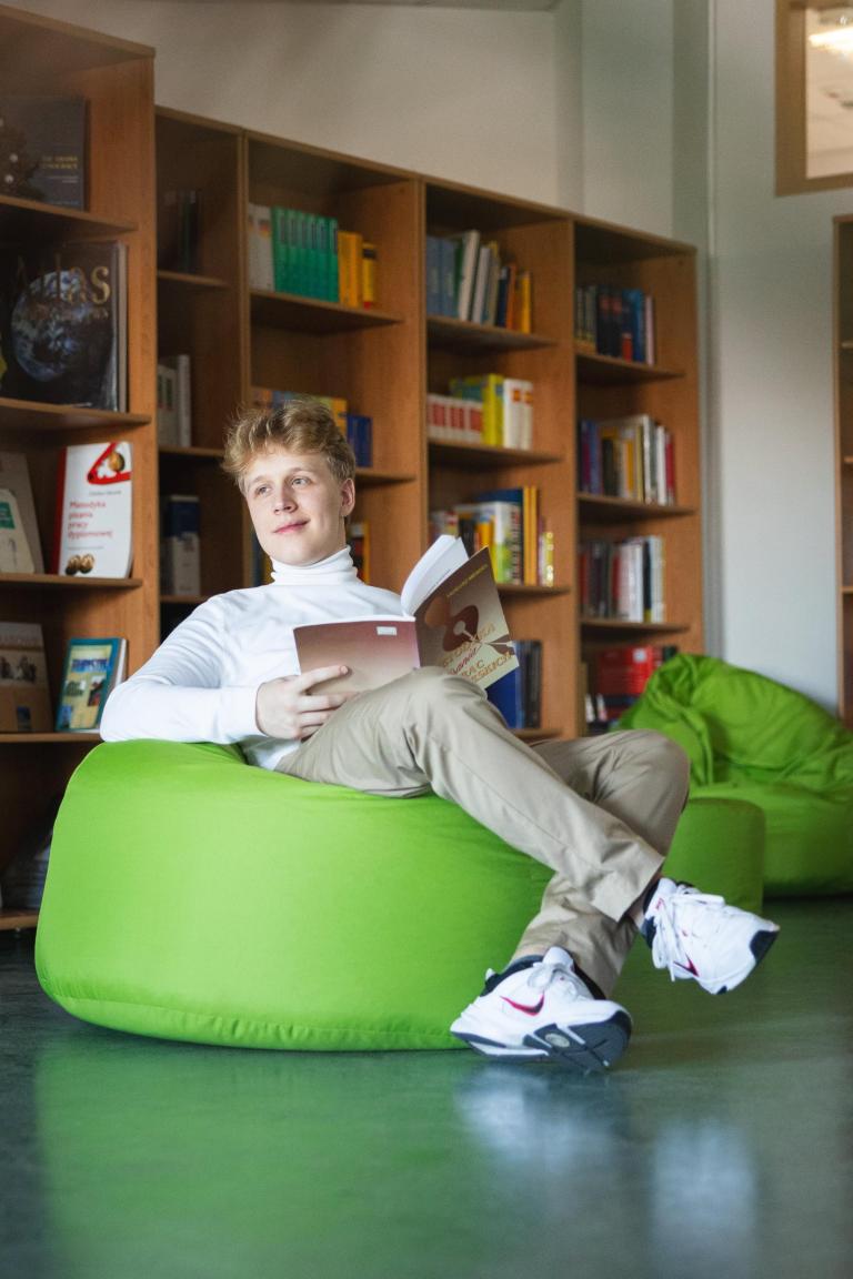 Strefa studenta | Uniwersytet WSB Merito Łódź: Uczeń czyta książkę w bibliotece Uniwersytetu WSB Merito w Łodzi