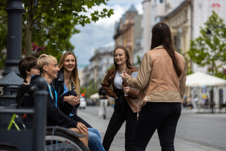 Strefa studenta | Uniwersytet WSB Merito Łódź: Grupka studentów rozmawia śmiejąc się na mieście.