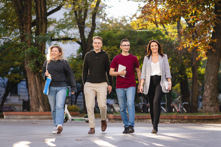 Certyfikaty językowe | Uniwersytet WSB Merito Łódź: 4 studentów Uniwersytetu WSB Merito w Łodzi w wesołej atmosferze idzie przez park