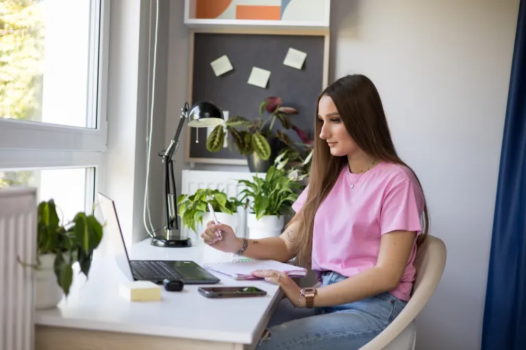 Studentka siedzi przy biurku i przygotowuje się do zajęć
