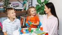 Pedagogika | Studia II stopnia w Opolu | Uniwersytet WSB Merito Opole: Młoda kobieta zajmuje się dwójką dzieci