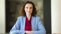 Kadry i płace | Studia podyplomowe w Opolu | Uniwersytet WSB Merito Opole: Główna grafika: Opole - studia podyplomowe - Kadry i płace - Kobieta siedząca za biurkiem, przed nią leżą notatki