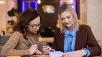 Zarządzanie w oświacie | Studia podyplomowe w Opolu | Uniwersytet WSB Merito Opole: Główna grafika: Opole - studia podyplomowe - Zarządzanie w oświacie - Dwie kobiety przeglądające notatki