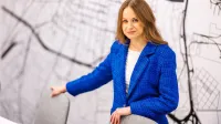 Doradztwo podatkowe | Uniwersytet WSB Merito Opole: Główna grafika: Opole - studia II stopnia - specjalność Doradztwo podatkowe - Kobieta w niebieskiej marynarce, stoi za stołem konferencyjnym