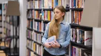 Wyniki wyszukiwania | Uniwersytet WSB Merito Opole: Główna grafika: Opole - studia II stopnia - specjalność Pedagogika resocjalizacyjna z socjoterapią - Dziewczyna opierająca się o regał z książkami