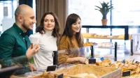 Dietetyka | Studia II stopnia w Opolu | Uniwersytet WSB Merito Opole: Główna grafika: Opole - studia II stopnia- Dietetyka - studenci stoją w piekarni i patrzą na gablotę z pieczywem