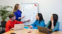 Główna grafika: Opole - studia I stopnia licencjackie - Pedagogika: Pedagogika: Pedagogika opiekuńczo-wychowawcza z pedagogiką Montessori- studenci rozmawiają w sali lekcyjnej i piszą na tablicy markerem