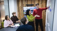 Główna grafika: Opole - studia podyplomowe - Copywriting sprzedażowy z AI - uczestnicy studiów podyplomowych analizują treści z tablicy 