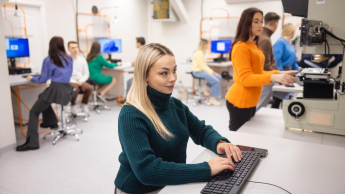 Logistyka | Studia I stopnia w Opolu | Uniwersytet WSB Merito Opole: Blondynka w golfie pracuje przy komputerze. w tle inni studenci.