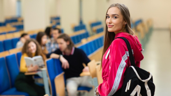 Pedagogika | Studia I stopnia w Opolu | Uniwersytet WSB Merito Opole: Młoda dziewczyna patrzy w obiektyw a tle widać grupę dziewcząt