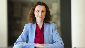 Kadry i płace | Studia podyplomowe w Opolu | Uniwersytet WSB Merito Opole: Główna grafika: Opole - studia podyplomowe - Kadry i płace - Kobieta siedząca za biurkiem, przed nią leżą notatki