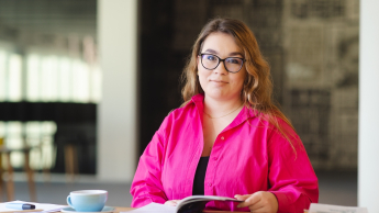 Rachunkowość od podstaw | Studia podyplomowe w Opolu | Uniwersytet WSB Merito Opole: Główna grafika: Opole - studia podyplomowe - Rachunkowość od podstaw - Kobieta siedząca za biurkiem, na biurku leżą książki, notesy i filiżanka kawy