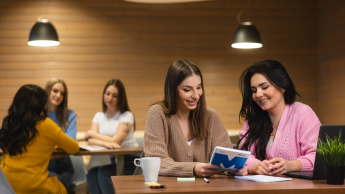 Digital marketing | Studia II stopnia w Opolu | Uniwersytet WSB Merito Opole: Główna grafika: Opole - studia II stopnia - specjalnosć Digital marketing - Dwie kobiety siedzące w kawiarni, przeglądają notatki