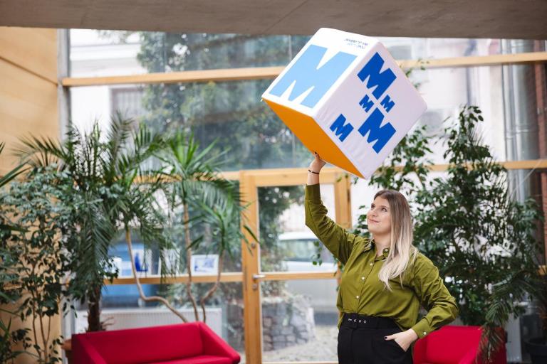 Światowy Tydzień Przedsiębiorczości | Uniwersytet WSB Merito Opole: Studentka trzymająca na jednej ręce dużą kostkę z logotypami Uniwersytetu WSB Merito Opole
