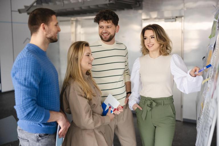 Prawo w biznesie | Studia I stopnia w Opolu | Uniwersytet WSB Merito Opole: Na zdjęciu grupa studentów stojąca przed tablicą, do której doczepione są kartki z notatkami.