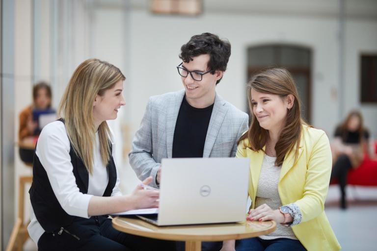 Prawo w biznesie | Studia I stopnia w Opolu | Uniwersytet WSB Merito Opole: Grupa studentów stojąca przed komputerem, spoglądająca na siebie