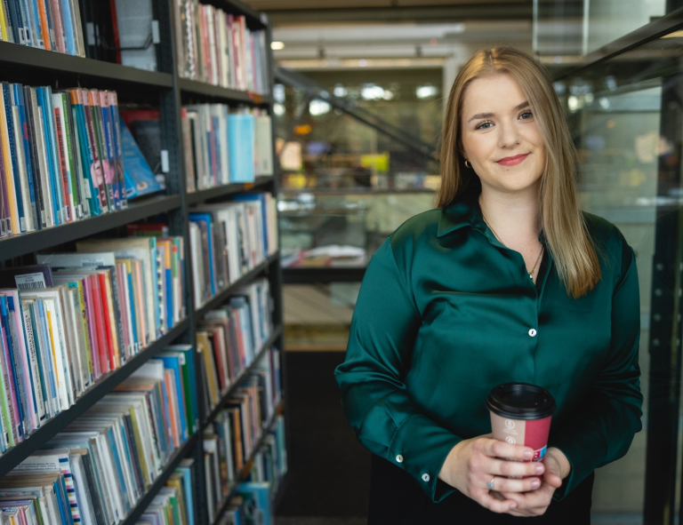 Psychologia i zarządzanie kapitałem ludzkim | Studia II stopnia ze studiami podyplomowymi  | Uniwersytet WSB Merito Opole: Studentka stojąca między regałami w bibliotece