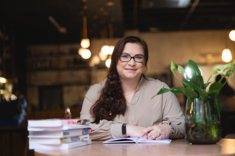 Pośrednictwo pracy | Uniwersytet WSB Merito Opole: Główna grafika: Opole - studentka siedząca w kawiarni, obok stos książek