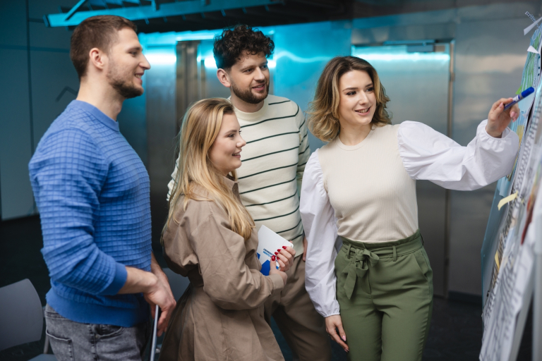 Cyfrowy uniwersytet | Uniwersytet WSB Merito Opole: Studenci oglądający notatki przypięte na dużej tablicy