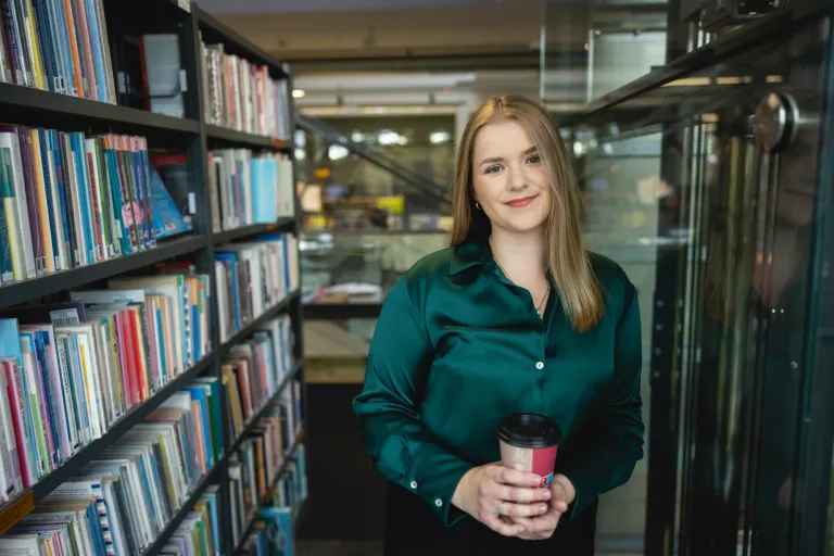 Wywiad i detektywistyka | Studia II stopnia w Opolu | Uniwersytet WSB Merito Opole: Studentka stojąca między regałami w bibliotece