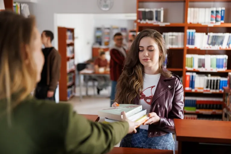 Psychodietetyka i terapia zaburzeń odżywiania | Studia II stopnia w Opolu | Uniwersytet WSB Merito Opole: Studentka odbiera książkę z biblioteki