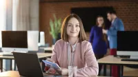 Podatki i doradztwo podatkowe | Studia podyplomowe w Poznaniu | Uniwersytet WSB Merito w Poznaniu: Kobieta przy laptopie, pracująca w nowoczesnej przestrzeni biurowej.