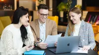 BIM Manager – nowoczesne zarządzanie inwestycjami budowlanymi | Studia podyplomowe w Poznaniu | Uniwersytet WSB Merito w Poznaniu: Trójka młodych dorosłych omawia dokumenty przy laptopie