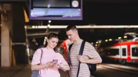 Manager bezpieczeństwa biznesu | Studia I stopnia w Poznaniu | Uniwersytet WSB Merito w Poznaniu: Dwójka studentów sprawdza rozkład jazdy pociągów na jednym z Poznańskich peronów.