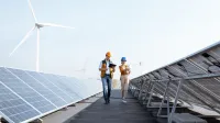 Efektywność energetyczna, odnawialne źródła energii i inne narzędzia prowadzące do transformacji energetycznej | Studia podyplomowe w Poznaniu | Uniwersytet WSB Merito w Poznaniu: dwie osoby idę pomiędzy panelami słonecznymi