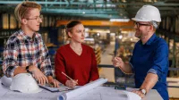 Inżynieria zarządzania - studia inżynierskie | Studia I stopnia w Poznaniu | Uniwersytet WSB Merito w Poznaniu: grupa stoi przed planem, noszą kaski ochronne