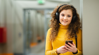 Marketing w cyfrowej transformacji | Studia II stopnia ze studiami podyplomowymi  | Uniwersytet WSB Merito w Poznaniu: Studentka WSB Merito Poznań słucha muzyki na korytarzu uczelni