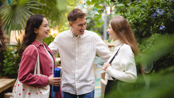 Student i 2 studentki rozmawiają w parku 