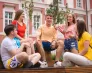 Drzwi Otwarte Uniwersytetu WSB Merito w Poznaniu | Aktualności | Uniwersytet WSB Merito w Poznaniu: 5 studentów siedzi na ławce w centrum miasta i rozmawiają w wesołej atmosferze