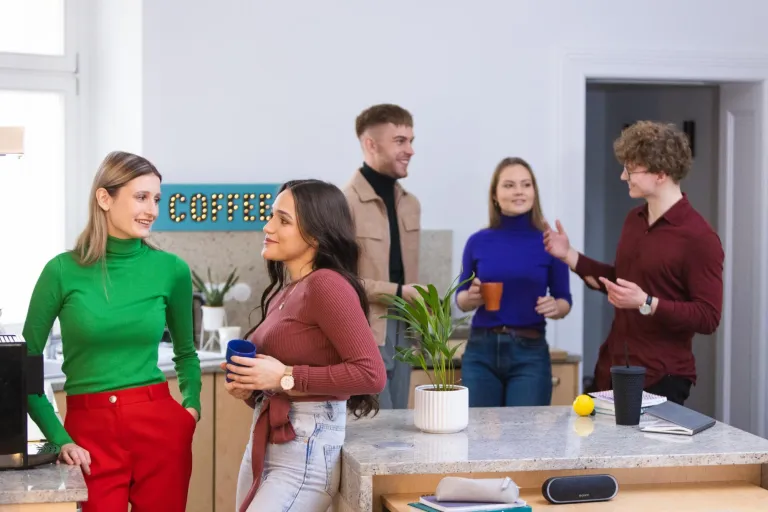 HR Business Partner | Studia II stopnia w Poznaniu | Uniwersytet WSB Merito w Poznaniu: Grupa młodych osób spędza czas w kuchni przy kawie