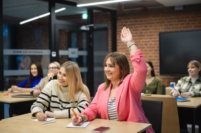 Sprzedaż w innowacyjnym przedsiębiorstwie | Studia II stopnia w Poznaniu | Uniwersytet WSB Merito w Poznaniu: Studentki biorą aktywny udział w zajęciach, jedna z nich z uśmiechem podnosi rękę
