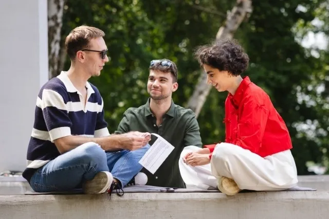 Bezpieczeństwo wewnętrzne | Studia II stopnia w Poznaniu | Uniwersytet WSB Merito w Poznaniu: Troje studentów siedzi na betonowej ławce na świeżym powietrzu