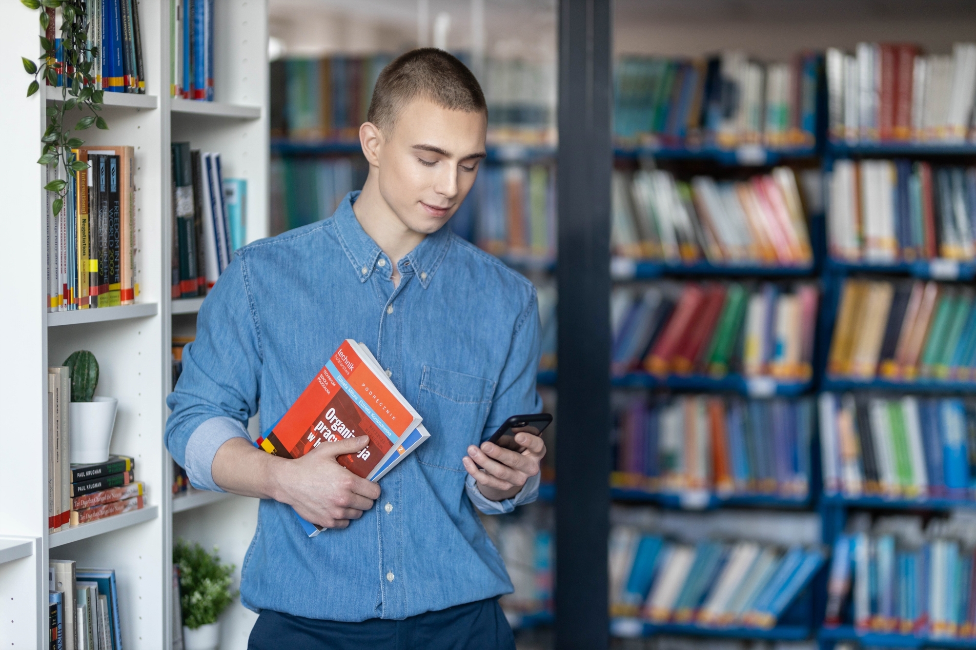 Chłopak w bibliotece trzymający telefon