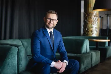 Studia MBA i EMBA | Uniwersytet WSB Merito: Uczestnik MBA na korytarzu uczelni pozuje- Uniwersytety WSB Merito