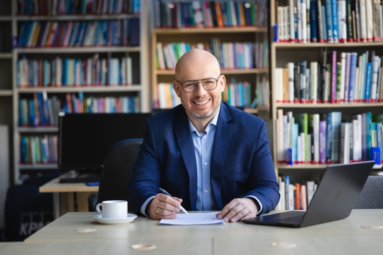Studia MBA i EMBA | Uniwersytet WSB Merito: Słuchacz Uniwersytetu WSB Merito siedzi przy biurku i wypełnia dokument
