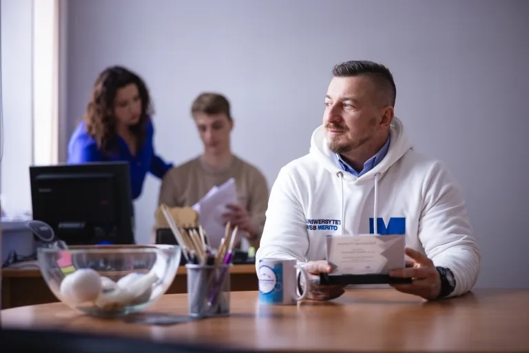 Wyniki wyszukiwania | Uniwersytet WSB Merito: Mężczyzna siedzący przy biurku, patrzący w stronę okna