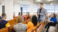 Przygotowanie pedagogiczne – dla nauczycieli teoretycznych przedmiotów zawodowych | Studia podyplomowe w Szczecinie | Uniwersytet WSB Merito Szczecin: Wykładowca Uniwersytetu WSB Merito prowadzący dyskusję ze studentami w sali wykładowej.