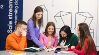 Przygotowanie pedagogiczne – dla nauczycieli przedmiotów lub zajęć prowadzonych w szkole podstawowej i ponadpodstawowej | Studia podyplomowe w Szczecinie | Uniwersytet WSB Merito Szczecin: Grupa studentów Uniwersytetu WSB Merito wspólnie pracuje nad materiałami, ucząc się i wymieniając pomysły w nowoczesnej przestrzeni edukacyjnej.