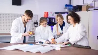 Zarządzanie produkcją | Studia podyplomowe w Szczecinie | Uniwersytet WSB Merito Szczecin: Grupa studentów w fartuchach w sali laboratoryjnej